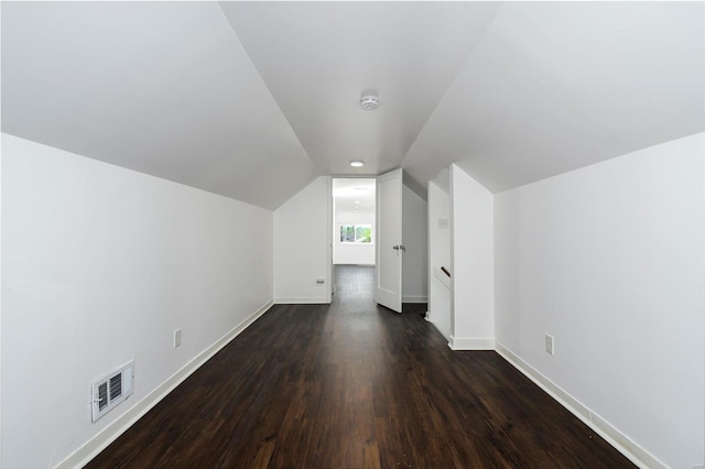 additional living space featuring baseboards, visible vents, dark wood-style floors, and vaulted ceiling
