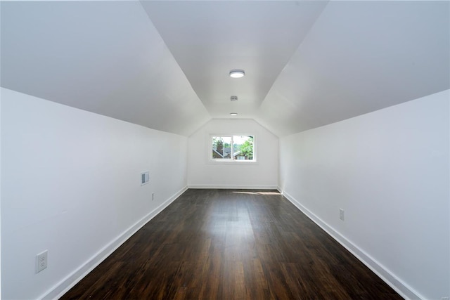 bonus room featuring visible vents, baseboards, dark wood-type flooring, and vaulted ceiling