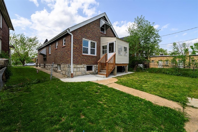 rear view of house with fence, a patio, a yard, and brick siding