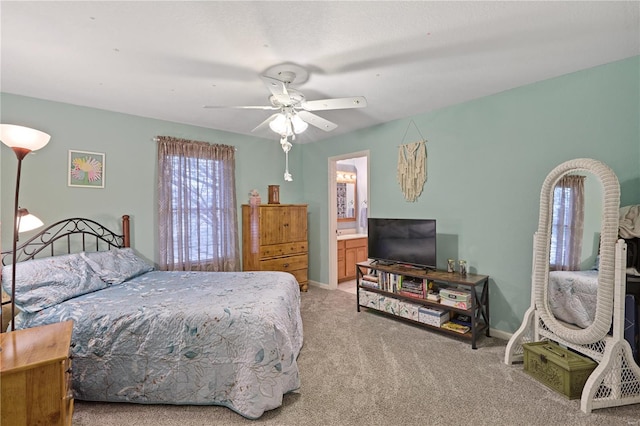 bedroom featuring baseboards, ensuite bathroom, a ceiling fan, and light colored carpet