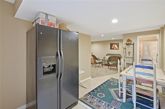kitchen with recessed lighting, light colored carpet, black refrigerator with ice dispenser, and baseboards