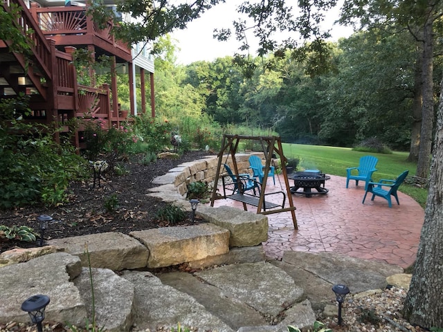 view of yard with a wooden deck, stairs, a fire pit, and a patio area