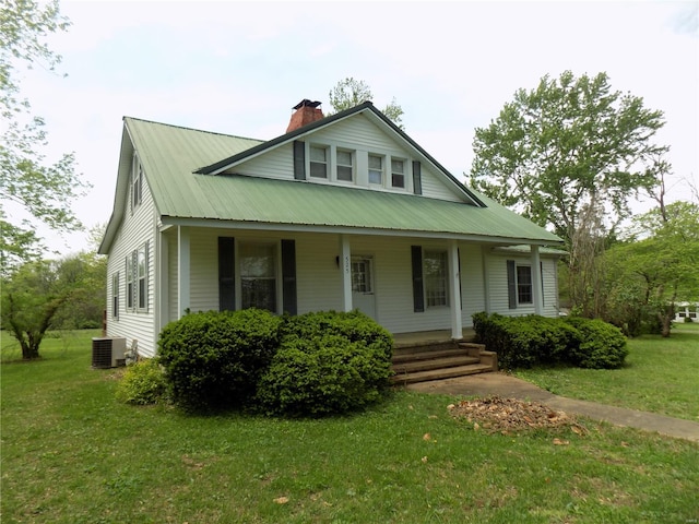 view of front of property with a front lawn, central AC, covered porch, a chimney, and metal roof