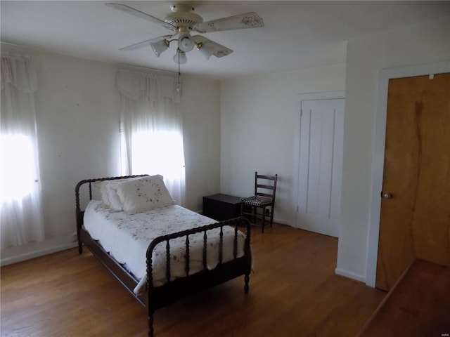 bedroom featuring a ceiling fan, baseboards, and wood finished floors