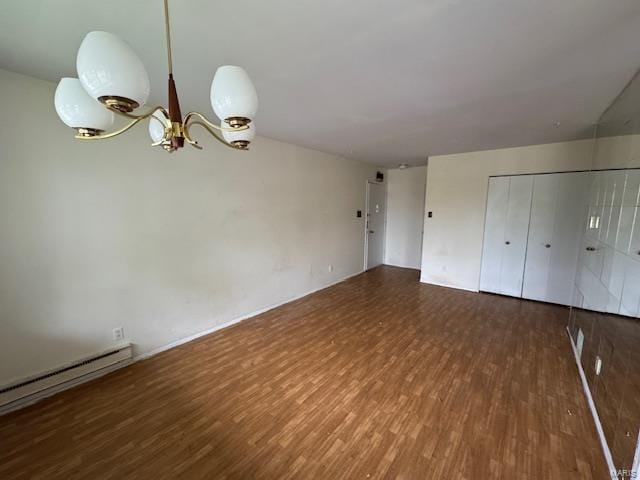 interior space with baseboard heating, an inviting chandelier, wood finished floors, and a closet