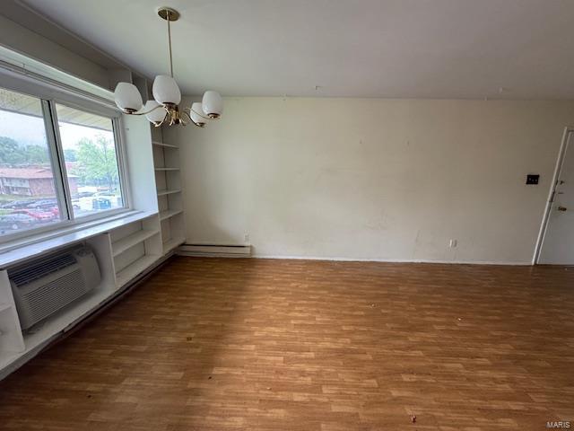 unfurnished dining area featuring a wall mounted air conditioner, wood finished floors, and a notable chandelier