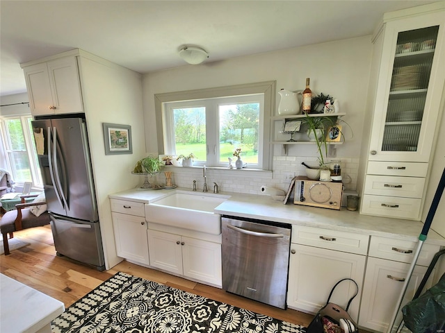 kitchen with light countertops, white cabinetry, tasteful backsplash, a sink, and stainless steel appliances