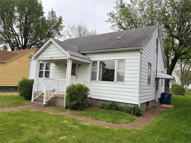 bungalow-style home featuring roof with shingles and a front lawn