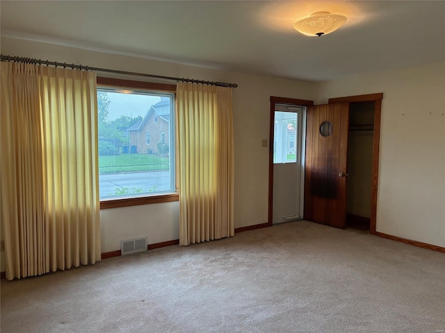 empty room featuring visible vents, carpet flooring, and baseboards