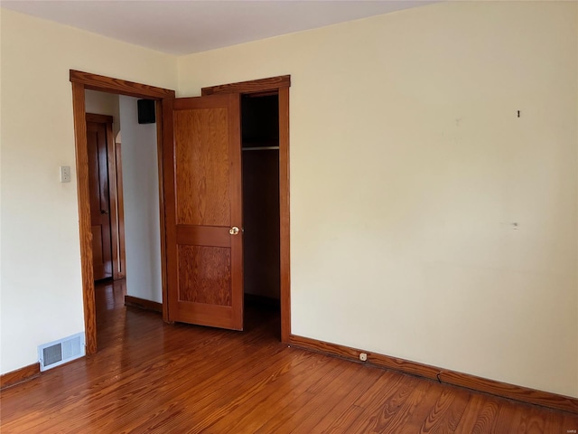 unfurnished bedroom featuring visible vents, baseboards, and wood finished floors