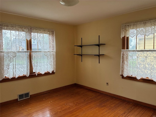 unfurnished room with visible vents, baseboards, and wood finished floors