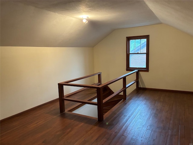 additional living space featuring baseboards, vaulted ceiling, and dark wood-style flooring
