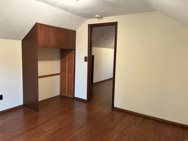 additional living space with dark wood-style flooring, baseboards, and vaulted ceiling