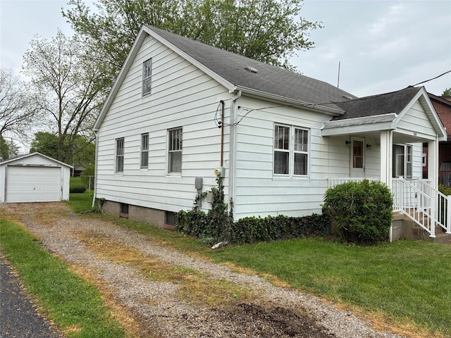 view of property exterior featuring roof with shingles, a garage, dirt driveway, a lawn, and an outdoor structure