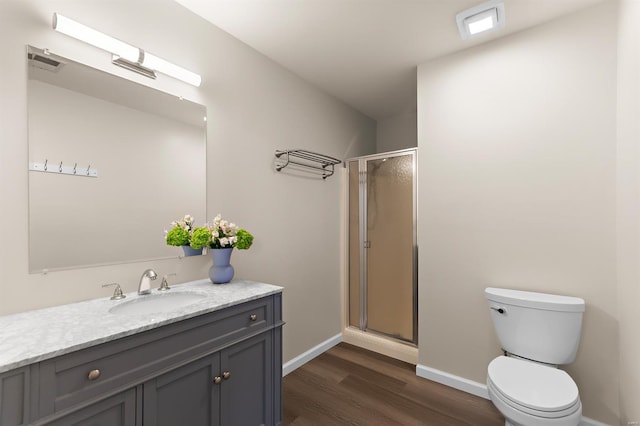 bathroom with a stall shower, wood finished floors, vanity, baseboards, and toilet