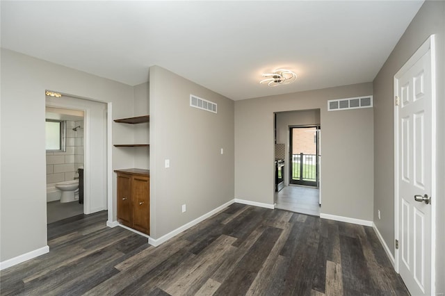 empty room with baseboards, dark wood-style flooring, and visible vents