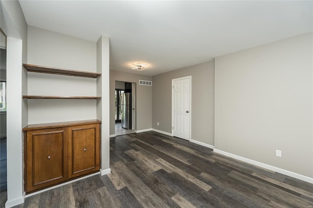 unfurnished living room with baseboards, dark wood-style floors, and visible vents