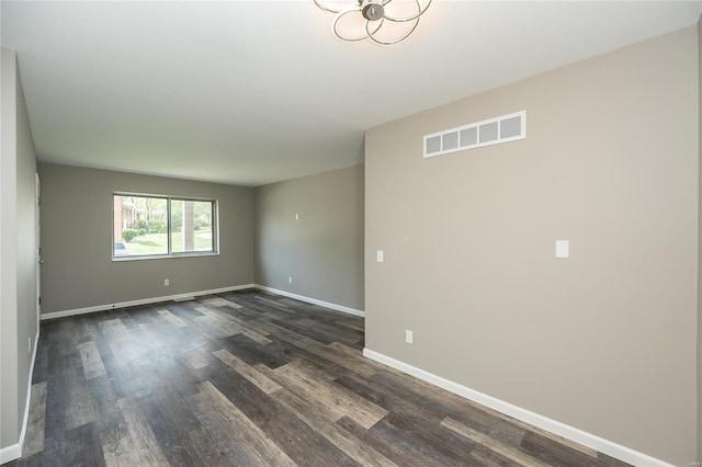 unfurnished room with visible vents, baseboards, and dark wood-style floors