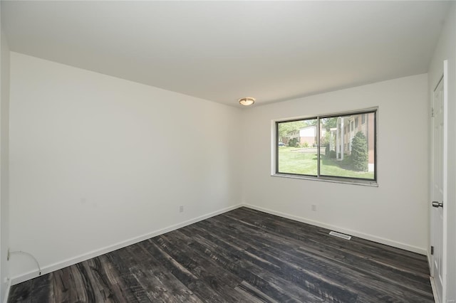 spare room featuring baseboards, dark wood finished floors, and visible vents