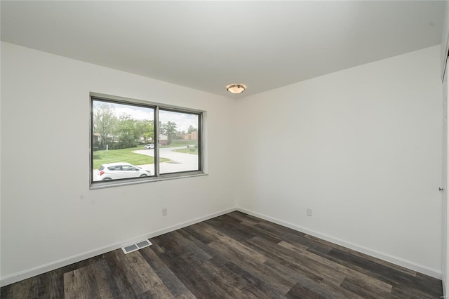 unfurnished room with dark wood-style flooring, baseboards, and visible vents