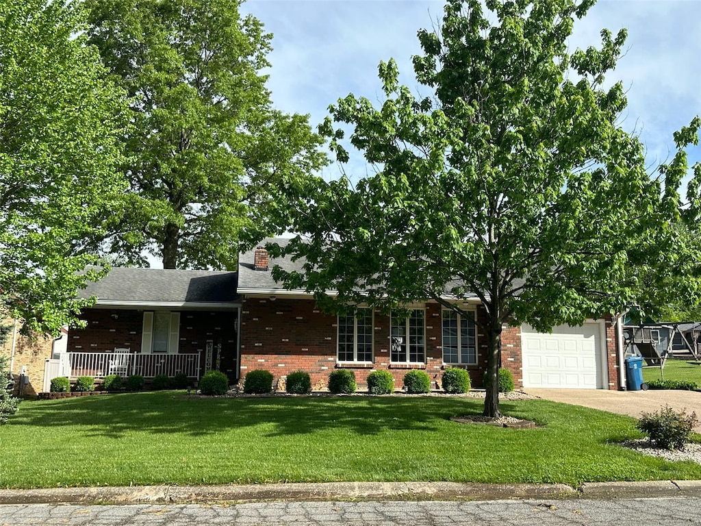 view of front of house with a front lawn, brick siding, a garage, a porch, and driveway
