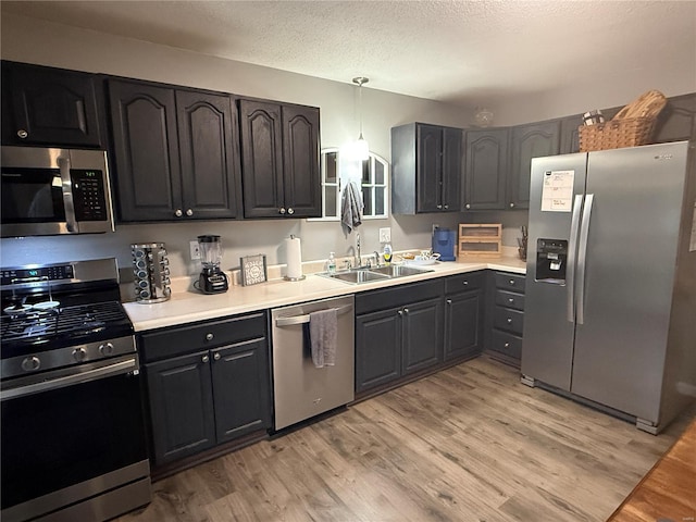 kitchen featuring a sink, light wood-style floors, stainless steel appliances, and a textured ceiling