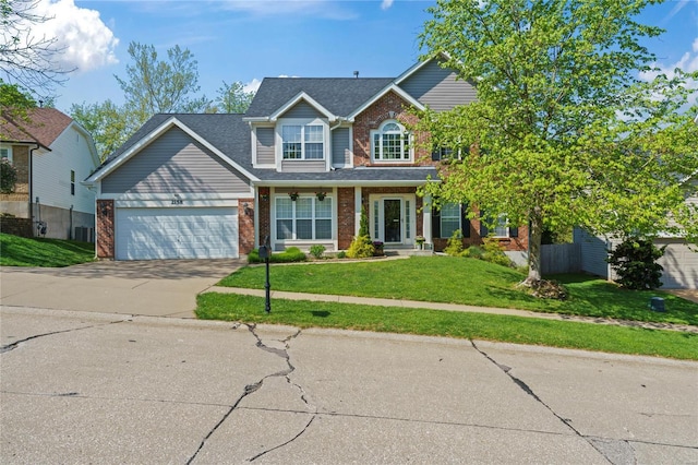 traditional-style house featuring an attached garage, driveway, a front lawn, and brick siding