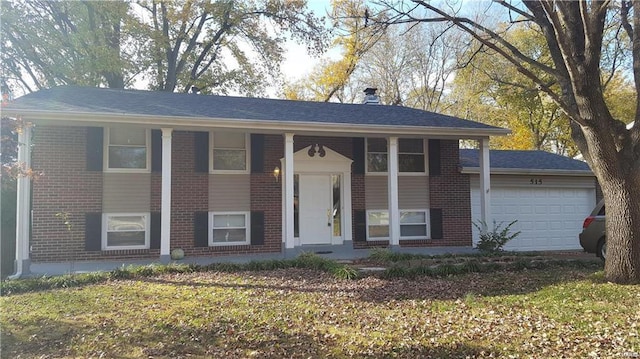 raised ranch featuring brick siding, an attached garage, and covered porch