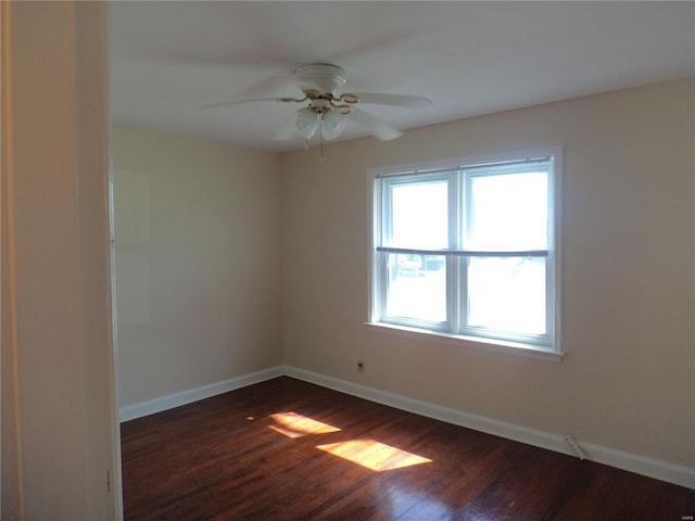 spare room featuring a ceiling fan, baseboards, and dark wood-type flooring