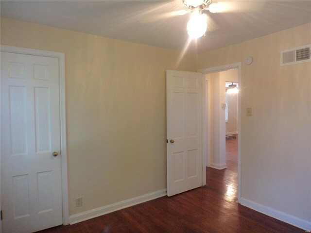 unfurnished bedroom featuring visible vents, dark wood-style flooring, and baseboards