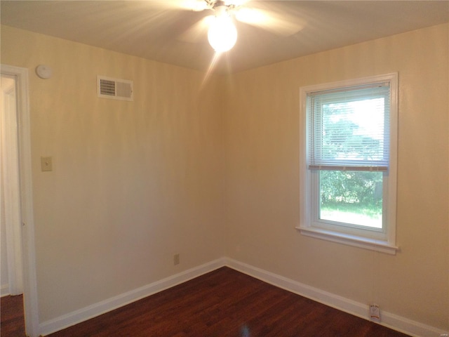 unfurnished room featuring a ceiling fan, baseboards, visible vents, and dark wood-type flooring