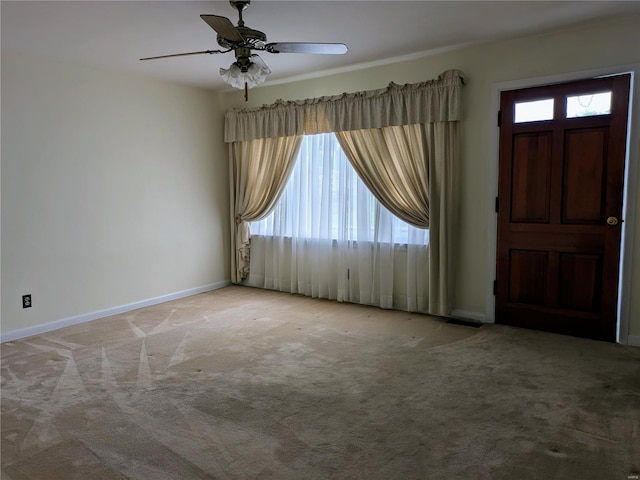 carpeted foyer featuring baseboards and ceiling fan