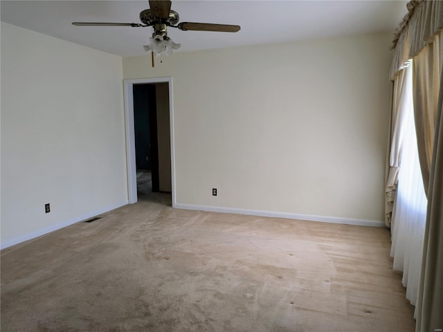 empty room featuring light colored carpet, baseboards, and ceiling fan