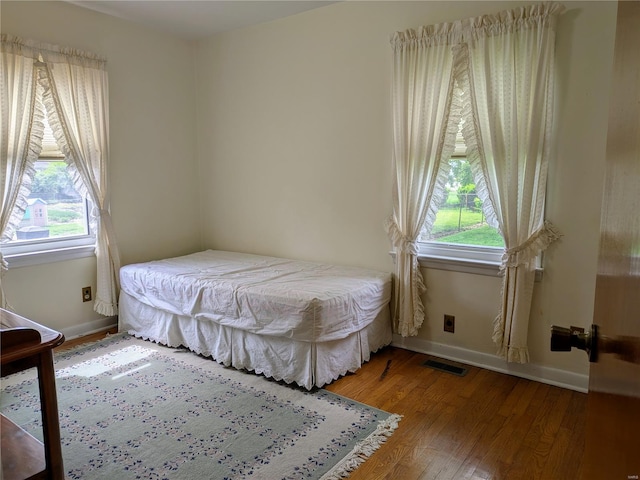 bedroom with baseboards, visible vents, multiple windows, and light wood-style flooring