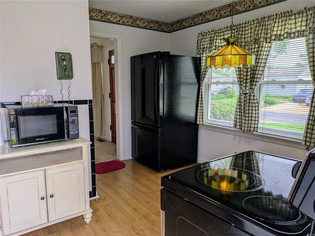kitchen with light wood-style floors, light countertops, white cabinets, and black appliances