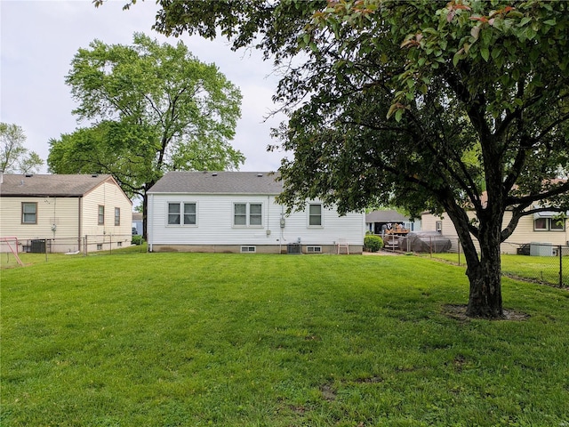 rear view of house featuring a lawn, fence, and cooling unit