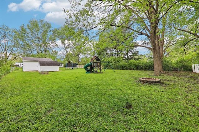 view of yard with an outdoor structure, a fire pit, a shed, a playground, and a trampoline