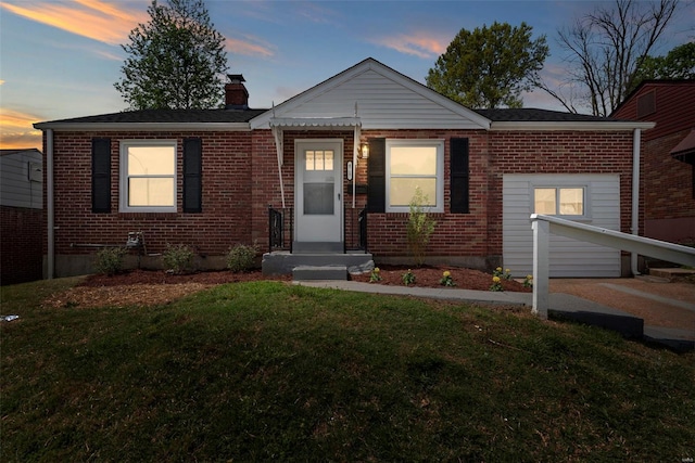 view of front of house with a chimney, a yard, and brick siding