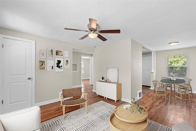 living room with baseboards, a ceiling fan, wood finished floors, and visible vents