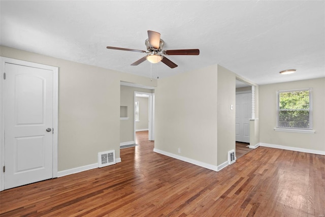 spare room with ceiling fan, visible vents, and wood finished floors
