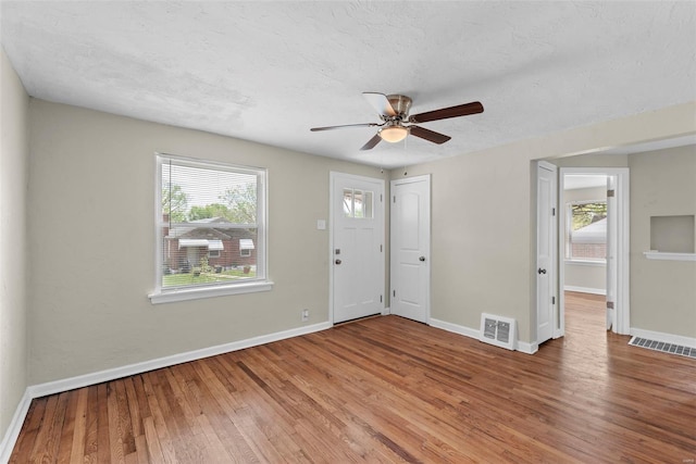 foyer entrance with wood-type flooring, baseboards, ceiling fan, and visible vents