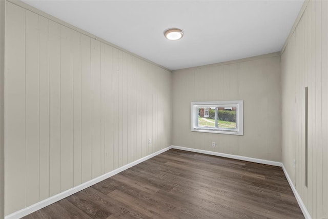 unfurnished room featuring baseboards and dark wood-style flooring