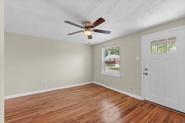 entrance foyer with a ceiling fan, baseboards, wood finished floors, and a textured ceiling