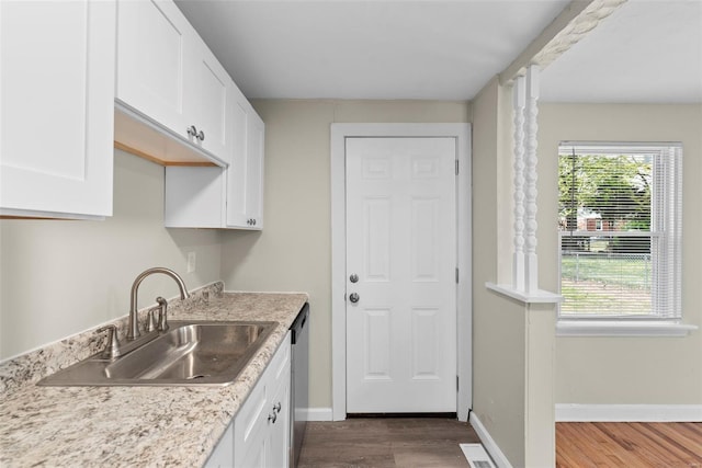 kitchen with stainless steel dishwasher, dark wood-style floors, light countertops, white cabinetry, and a sink