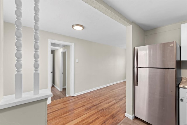 kitchen featuring light countertops, baseboards, freestanding refrigerator, and light wood-style flooring