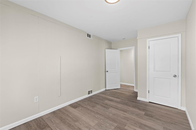 unfurnished room with baseboards, wood finished floors, and visible vents