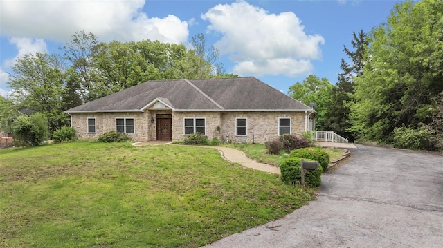 ranch-style home featuring a front lawn, stone siding, and aphalt driveway