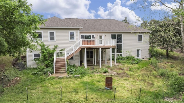 rear view of house featuring a lawn, stairs, a shingled roof, and a deck