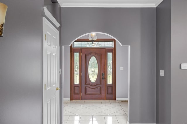foyer featuring a towering ceiling, arched walkways, baseboards, ornamental molding, and light tile patterned flooring
