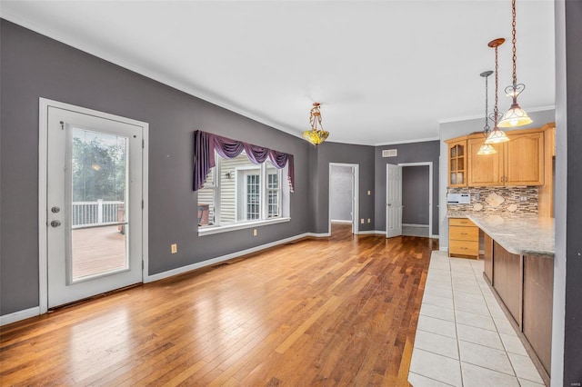 unfurnished dining area featuring baseboards, ornamental molding, and light wood finished floors